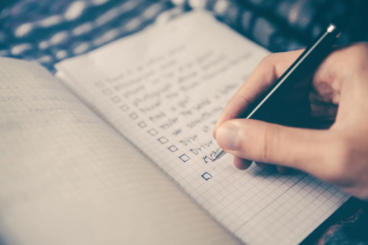 Mano che compila una check list su un quaderno